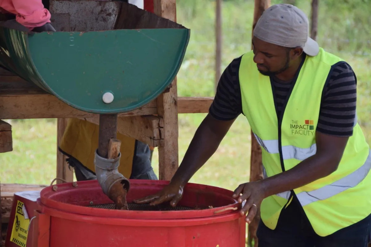 A worker feeds ore into a mechanised processing plant